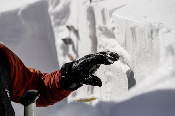 Ski guide explains the snow profile by cutting with a shovel © Claudia Ziegler Photography